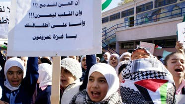 A Palestinian student shouts slogans as she carries a banner in Arabic that reads :" The eye is crying, the heart is sad, and we are mourning on your children Gaza," at the Yarmuk Palestinian refugee camp in Damascus, Syria. (File: AP)
