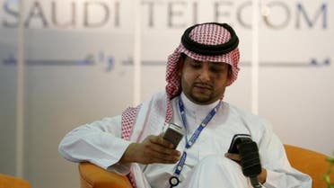 A Saudi man looks at his mobile phone in front of a Saudi Telecom sign in Riyadh April 25, 2005. (File: Reuters) 