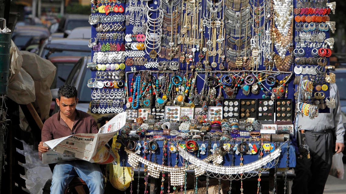 An Egyptian street vendor reads a newspaper while waiting for customers, one of many doing business in an informal economy at a time of high inflation and underemployment, in downtown Cairo, Egypt, Saturday, March 16, 2013. (AP)