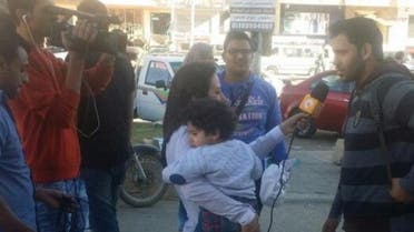 This picture of Lamia Hamdin holding her child as she interviewed people on a Cairo street sparked social media reactions. (Photo courtesy: Facebook)