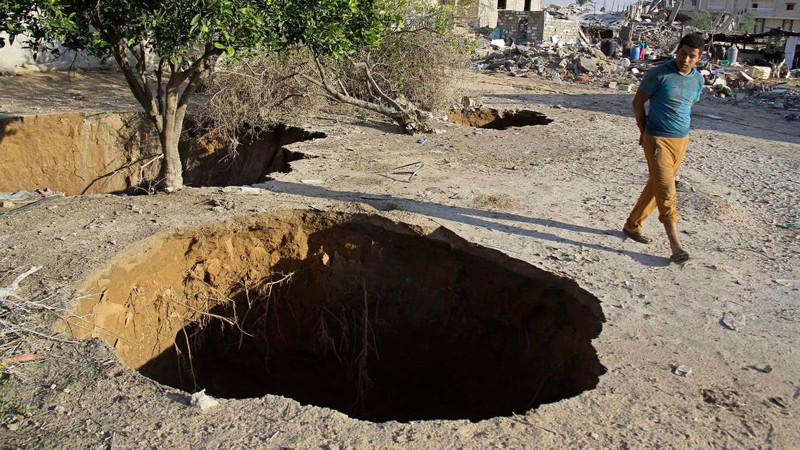 A young man walks by holes made by the Egyptian military to destroy smuggling tunnels connected to Gaza, as he visits an area on the Egyptian side of the border town of Rafah, northeast of Cairo, Egypt, Nov. 7, 2014. AP