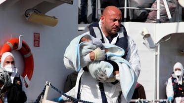 An officer carries a baby as migrants disembark from an Italian Coast Guard vessel after being rescued in Porto Empedocle, Sicily, southern Italy, Wednesday, March 4, 2015. AP