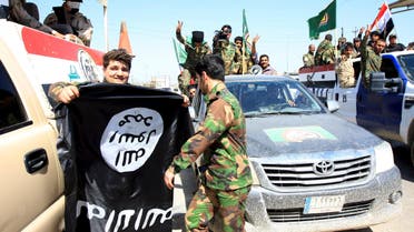 Paramilitary fighters hold an ISIS flag which they pulled down during victory celebrations after returning from Tikrit in Kerbala. (Reuters)