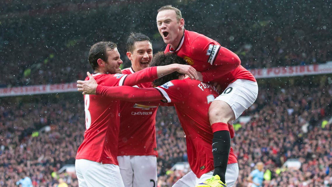 Manchester United's Marouane Fellaini, bottom right, celebrates with teammates including captain Wayne Rooney, top, after scoring during the English Premier League soccer match between Manchester United and Manchester City at Old Trafford Stadium, Manchester, England, Sunday, April 12, 2015. (AP Photo/Jon Super)