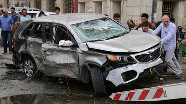 Iraqis try to lift a car at the site of a car bomb explosion at a convenience store in the Karrada neighborhood of Baghdad, Iraq, Friday, April 10, 2015. (AP)