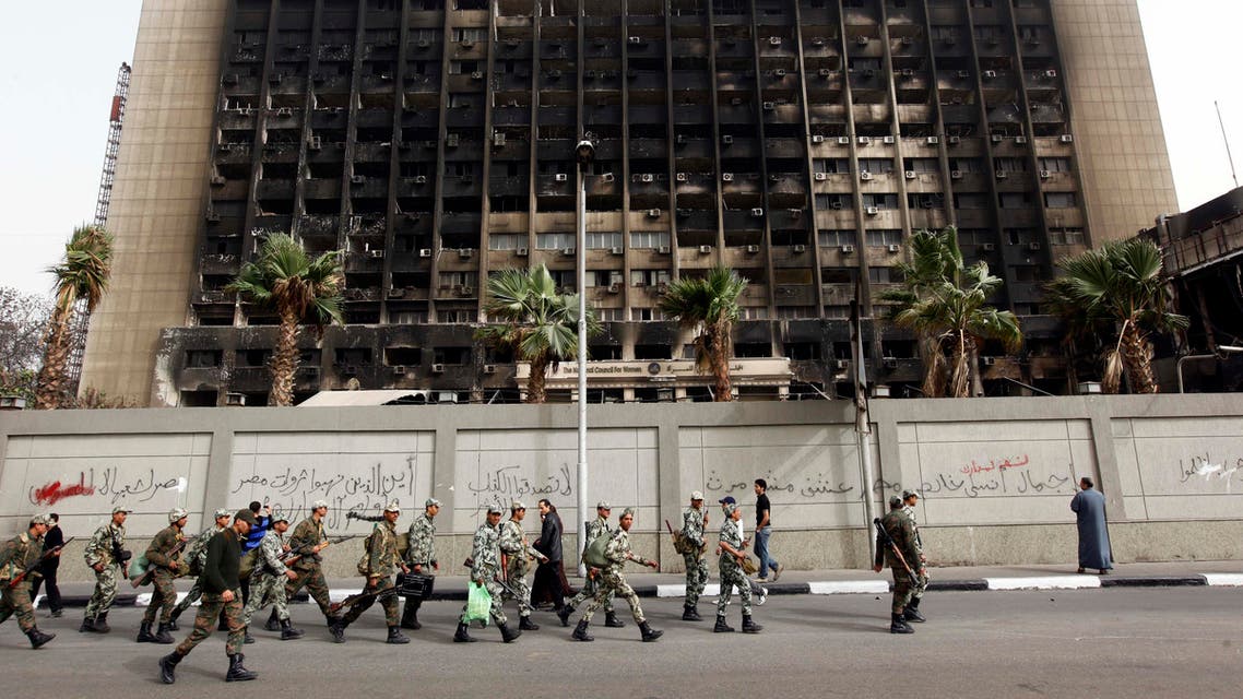 Army soldiers march in front of the burned down building of Hosni Mubarak's National Democratic Party in Cairo. (File: AP)