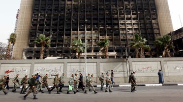 Army soldiers march in front of the burned down building of Hosni Mubarak's National Democratic Party in Cairo. (File: AP)