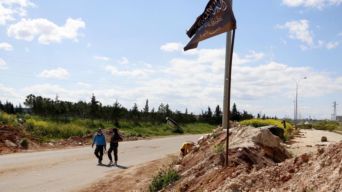 Members of al Qaeda's Nusra Front walk near the Nusra flag as it flutters at a checkpoint at the entrance of Idlib city, April 14, 2015. Reuters