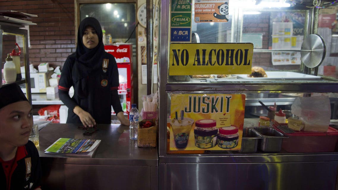 An Indonesia restaurant worker waits for customers as a no alcohol sign is displayed on the food stall in a tourist district in Jakarta. (AFP)