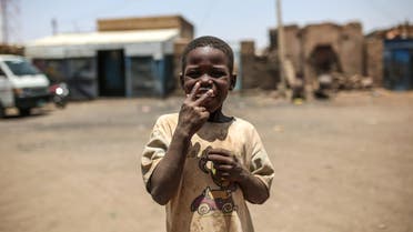 In this picture taken on Tuesday, April 14, 2015, a Sudanese boy gestures to the camera for a smoke, outside his home in Izba, an impoverished neighborhood on the outskirts of Khartoum, Sudan. Izba is one sign of how the constant internal wars, under Sudan's President Omar al-Bashir, have shaped, Khartoum. Before al-Bashir came to power, Izba was home to a community of Arab tribesmen who had settled here to be close to the capital. But through the 1990s and 2000s, it swelled with Sudanese fleeing war zones around the country. Now 70,000 people live crammed into Izba, an area of about a square mile. (AP Photo/Mosa'ab Elshamy)