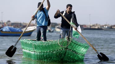  Palestinian Baha Abed (L) and his cousin Mohamed Abed paddle on their makeshift boat made of plastic bottles on April 18, 2015 at the port of Gaza City. (AFP)