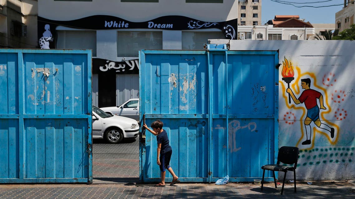 A Palestinian boys closes the gate of a United Nations school where hundreds of families sought refuge after fled their homes due to heavy Israeli missile strikes in Gaza City, Wednesday, July 23, 2014. (AP)