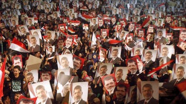 Members of the Muslim Brotherhood and supporters of Egypt's President Mohamed Mursi hold pictures of him as they react after the Egyptian army's statement was read out on state TV, at the Raba El-Adwyia mosque square in Cairo in this July 3, 2013 file photo. (Reuters)