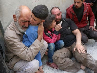 Grief-stricken Syrians sit on the pavement near a building that was targeted in a reported barrel bomb attack by Syrian government forces on the central al-Fardous rebel held neighbourhood of the northern Syrian city of Aleppo, on April 29, 2015, which left a number of people dead, according to locals. AFP