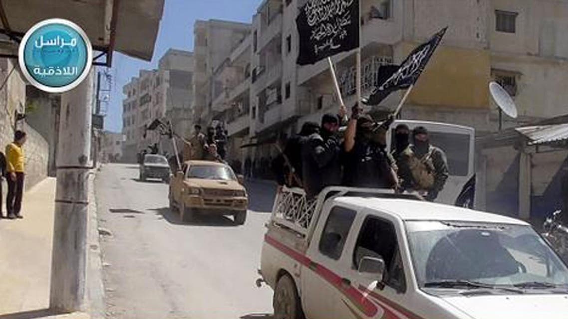 Nusra Front fighters standing on their vehicles and waving their group's flags as they tour the streets of Jisr al-Shughour, Idlib province, Syria. (AP)