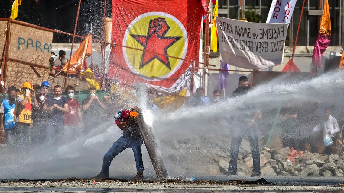 A protester takes cover from a Turkish riot police water canon during clashes in Taksim Square in Istanbul, Tuesday, June 11, 2013. Hundreds of police in riot gear forced their way through barricades in the square early Tuesday, pushing many of the protesters who had occupied the square for more than a week into the nearby Gezi park. (AP Photo/Vadim Ghirda)