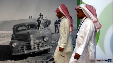 Saudi men walk by an advertisement for U.S. oil company Aramco during the Organization of the Petroleum Exporting Countries (OPEC) Summit in Riyadh, Saudi Arabia. (File: AP)