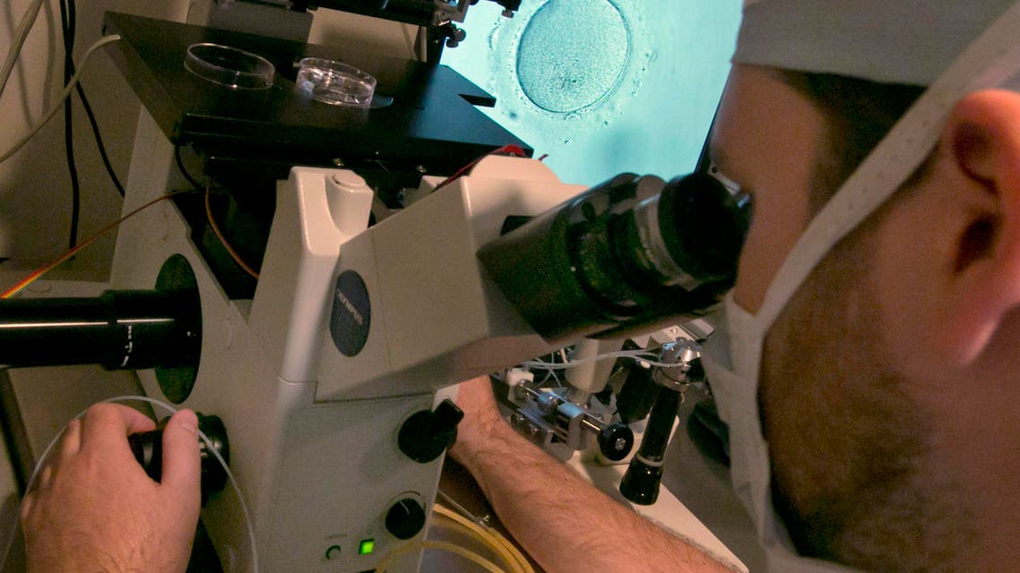 Embryologist Rick Slifkin uses a microscope to view an embryo, visible on a monitor, right, at Reproductive Medicine Associates of New York, in New York, Thursday, Oct. 3, 2013. Fertility clinics have put a new twist on how to make babies: A "two-mom" approach that lets female same-sex couples share the biological role. One woman's eggs are mixed in a lab dish with donor sperm, then implanted in the other woman who carries the pregnancy. (AP Photo/Richard Drew)