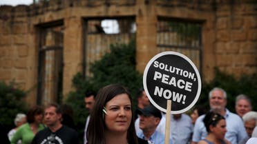 A woman holds a placard during a demonstration in favour of a peace settlement on divided Cyprus, outside a venue where leaders of estranged Greek and Turkish Cypriots met, in Nicosia, May 11, 2015. It was the first encounter of Greek Cypriot leader Nicos Anastasiades and Turkish Cypriot leader Mustafa Akinci since Akinci, a leftist moderate, won leadership elections in northern Cyprus on April 26. REUTERS/ Yiannis Kourtoglou