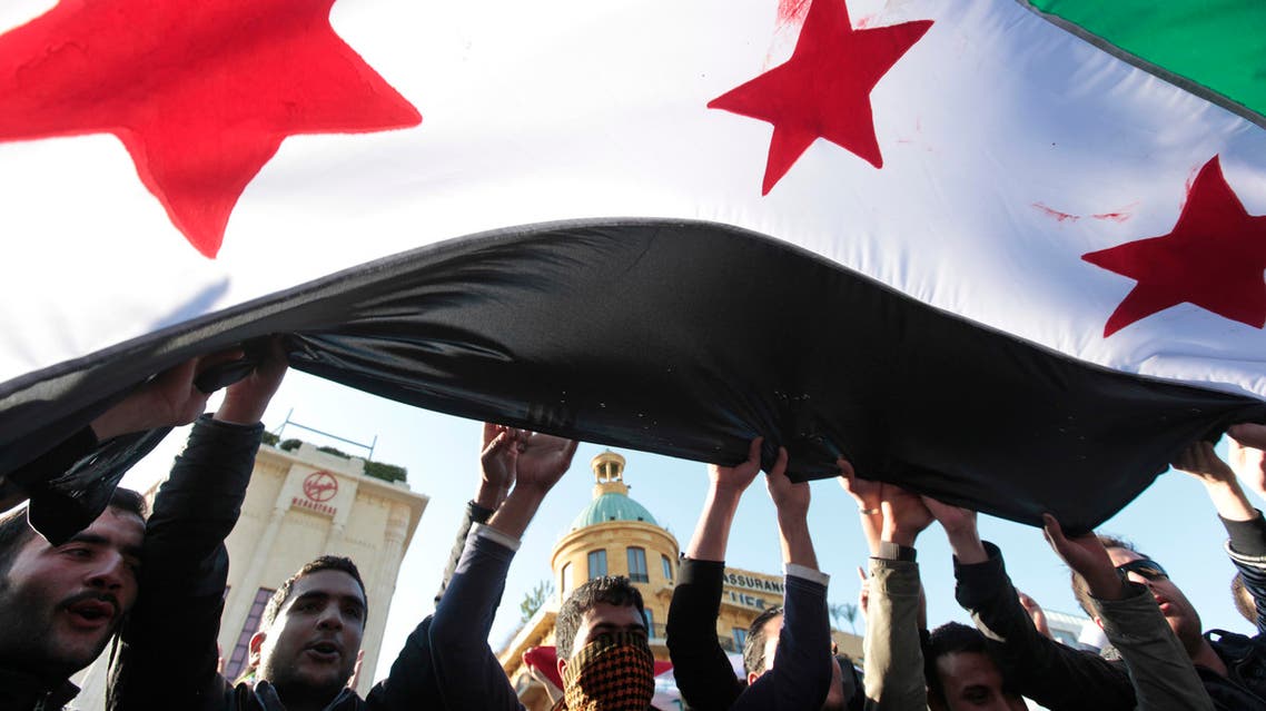Syrian citizens who live in Lebanon wave the Syrian revolution flag as they shout slogans against Syrian President Bashar Assad during an anti-Syrian regime protest held by Lebanese intellectuals, at the Martyrs Square in downtown Beirut, Lebanon, on Saturday March 17, 2012. Twin car bombs struck intelligence and security buildings in the Syrian capital on Saturday, killing at least 27 people and wounding nearly 100, according to state media. (AP Photo/Hussein Malla)