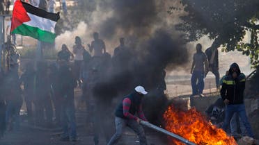 In this Nov. 9, 2014 file photo Israeli Arab protestors, one burning a traffic sign as another waves a Palestinians flag, clash with Israeli riot police in the Arab village of Kfar Kana, northern Israel. AP