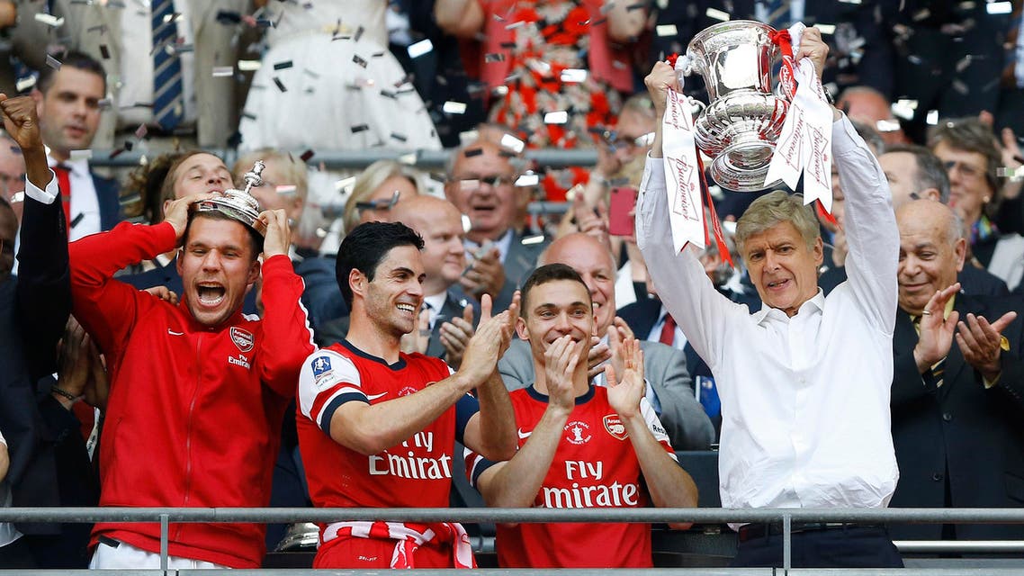 Arsenal's coach Arsene Wenger, right, hold the trophy aloft as he celebrates after his team won the English FA Cup final soccer match between Arsenal and Hull City at Wembley Stadium in London, Saturday, May 17, 2014. Arsenal won 3-2 after extra-time. (AP Photo/Kirsty Wigglesworth)