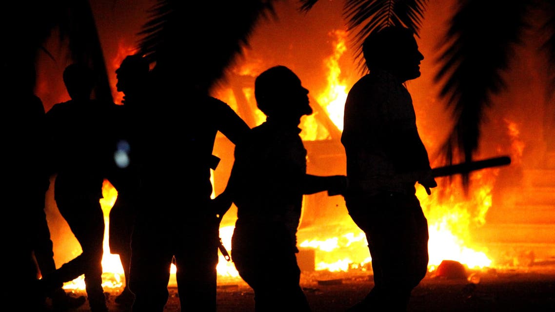 In this Friday, Sept. 21, 2012 file photo, Libyan civilians watch fires at an Ansar al-Shariah Brigades compound, after hundreds of Libyans, Libyan Military, and Police raided the Brigades base, in Benghazi, Libya. (AP)