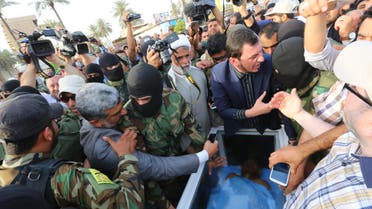 Civilians and members of the Iraqi Hezbollah Brigades gather around a glass-topped coffin as they prepare to deliver what they claim is the body of former Saddam Hussein deputy Izzat Ibrahim al-Douri in Baghdad, April 20, 2015 (AP)