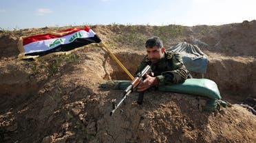 In this Sunday, Feb. 15, 2015 photo, a Shiite militia fighter aims his weapon with the Iraqi flag in the background. (AP)