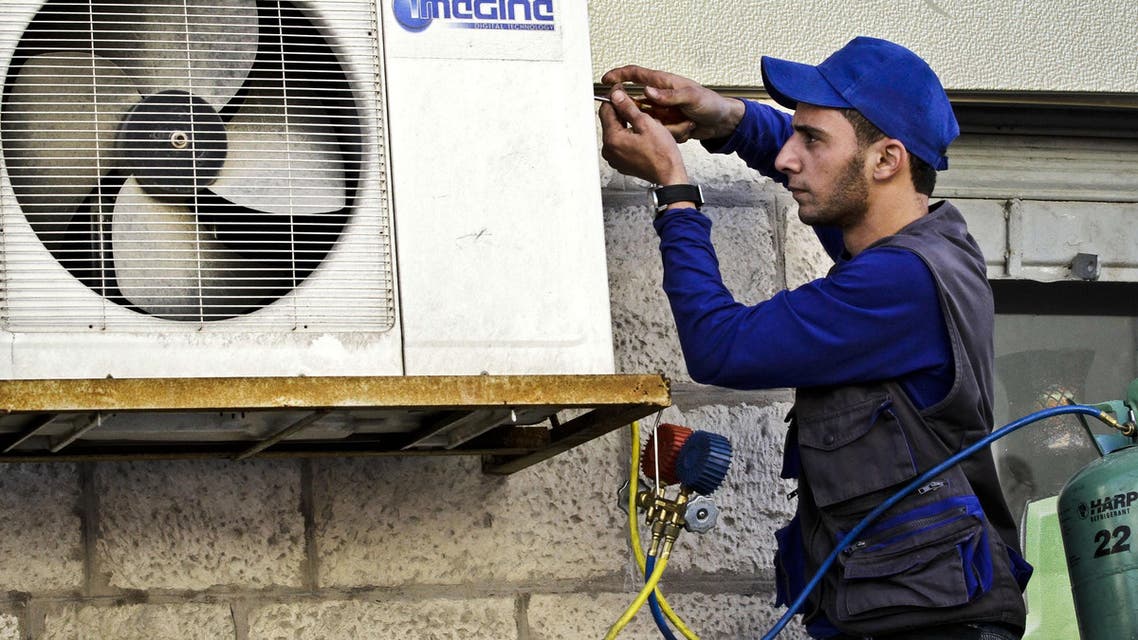 Mohammed Nabouti, a 21-year-old technician, fixes the air conditioner of a shop in Amman, Jordan AP