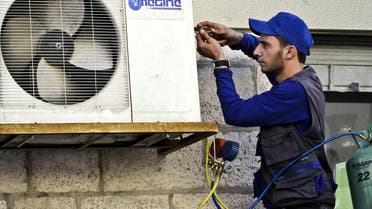 Mohammed Nabouti, a 21-year-old technician, fixes the air conditioner of a shop in Amman, Jordan AP