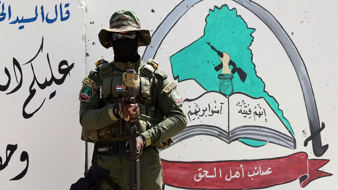 An Iraqi fighter of the Shiite militia Asaib Ahl al-Haq (The League of the Righteous) stands guard outside the militia's headquarters in the Iraqi city of Basra, as Shiite militias converged on Ramadi in a bid to recapture it from ISIS. AFP