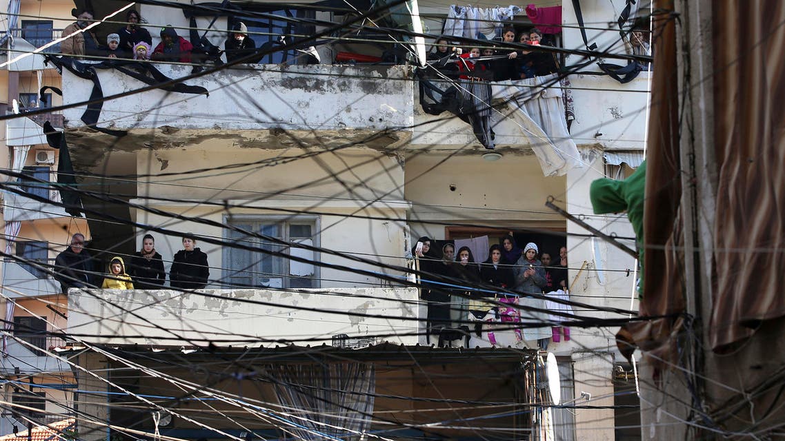 Alawite mourners seen through electricity wires stand on their balconies watching the funeral procession of those who were killed at a coffee shop where a suicide bombing struck it Saturday night, in a predominantly Alawite neighborhood of the northern port city of Tripoli, Lebanon, Sunday, Jan. 11, 2015. Syria's al-Qaida-linked Nusra Front claimed responsibility on Twitter for the blast that killed several people and wounded more than 30 in Tripoli's neighborhood of Jabal Mohsen, saying it was a twin suicide attack. (AP Photo/Hussein Malla)