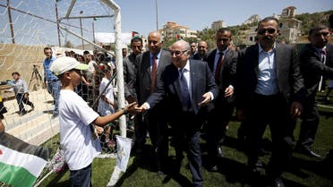 FIFA chief Sepp Blatter shakes hands with a Palestinian boy during his visit to Dura al-Qar' village in the West Bank city of Ramallah. Reuters 