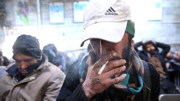 A drug addict smokes cigarette at drop-in center and shelter south of Tehran, Iran. (File: AP)