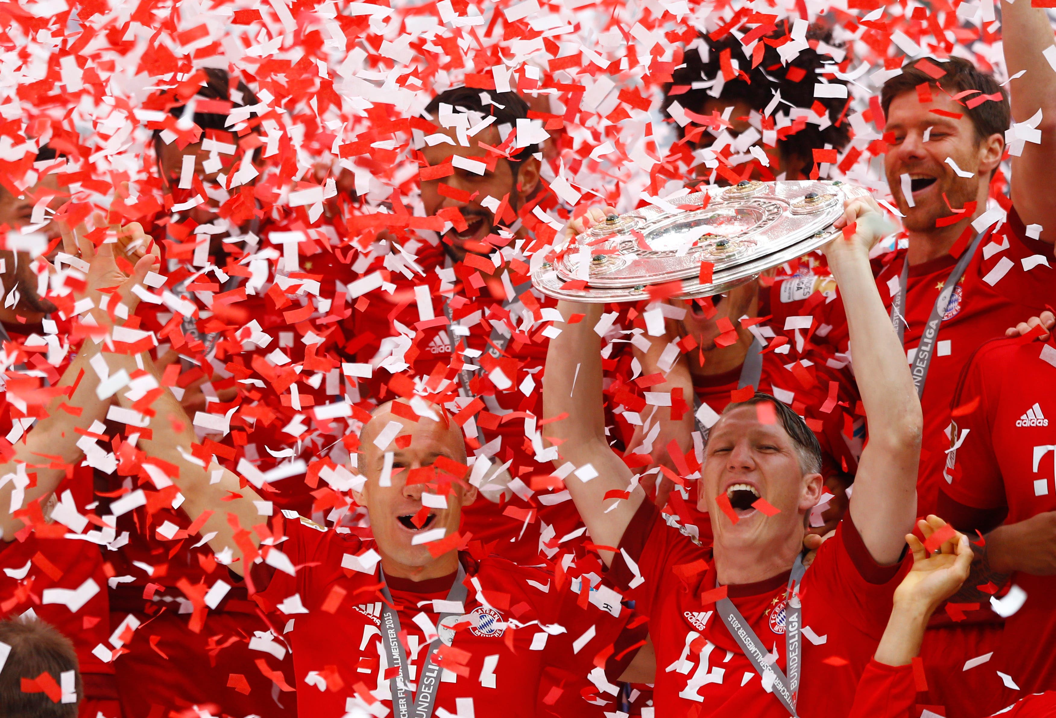 Bayern's Bastian Schweinsteiger, bottom right, lifts the trophy as his teammates Bayern's Arjen Robben from the Netherlands, left, and Bayern’s Xabi Alonso from Spain look on after the German first division Bundesliga soccer match between FC Bayern Munich and FSV Mainz 05 at the Allianz Arena in Munich, Germany, Saturday, May 23, 2015. (AP Photo/Matthias Schrader)