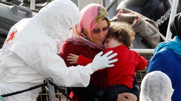 A woman holds her child as they disembark from the Iceland Coast Guard vessel Tyr, at the Messina harbor, Sicily, southern Italy, Wednesday, May 6, 2015. AP