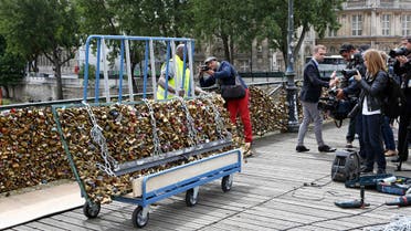 A Paris city employee removes a railing loaded with locks on the famed Pont des Arts bridge in Paris, Monday June 1, 2015. AP