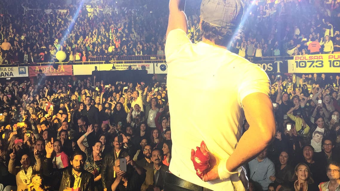In this photo provided by Francis Ramsden, Enrique Iglesias performs while holding his bloodied and bandaged right hand behind his back during a concert in Tijuana, Mexico on Saturday, May 30, 2015. A representative for the singer says in a statement to The Associated Press that Iglesias was "semi-treated" offstage after his fingers were sliced when he grabbed a drone during the concert. (Francis Ramsden via AP)