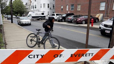 A local youth wheels his bicycle past law enforcement officials are gathered on a residential street in Everett, Massachusetts June 2, 2015. (Reuters)