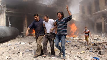 Syrian men help an injured person following a reported barrel bomb attack by Syrian government forces that hit an open market in the northern city of Aleppo, on June 3, 2015 - AFP 