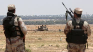  Palestinian militants of the Ezzedine al-Qassam Brigades, Hamas' armed wing, watch an Israeli bulldozer working along a barbed wire fence that separates Rafah in the southern Gaza Strip and the Israeli border, on June 03, 2015. AFP