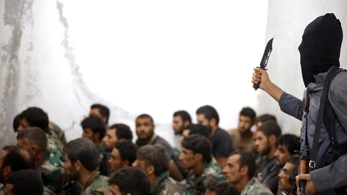 A fighter from ISIS, armed with a knife and an automatic weapon, next to captured Syrian army soldiers and officers. (File Photo: AP)