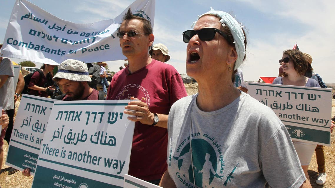 Palestinians, foreigners and Israeli peace activists hold banners and shout slogans as they demonstrate against the demolition of the southern West Bank Palestinian village of Susya and in support of the citizens in the southern area near the town of Hebron on June 5, 2015. (AFP)