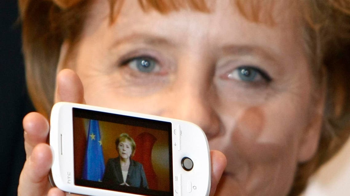 German Chancellor Angela Merkel holds a cell phone with a photo of her on the screen during her opening walk at the CeBIT in Hanover, northern Germany, on Tuesday, March 3, 2009.