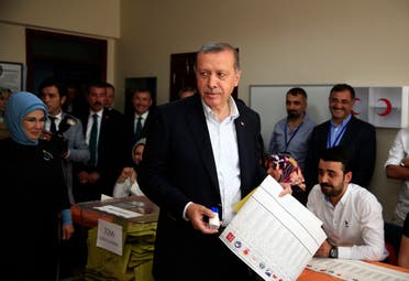 Turkey’s President Recep Tayyip Erdogan, centre, accompanied by his wife Emine, left, holds his ballot as he prepares to vote at a polling station in Istanbul, Turkey, Sunday, June 7, 2015. (AP)