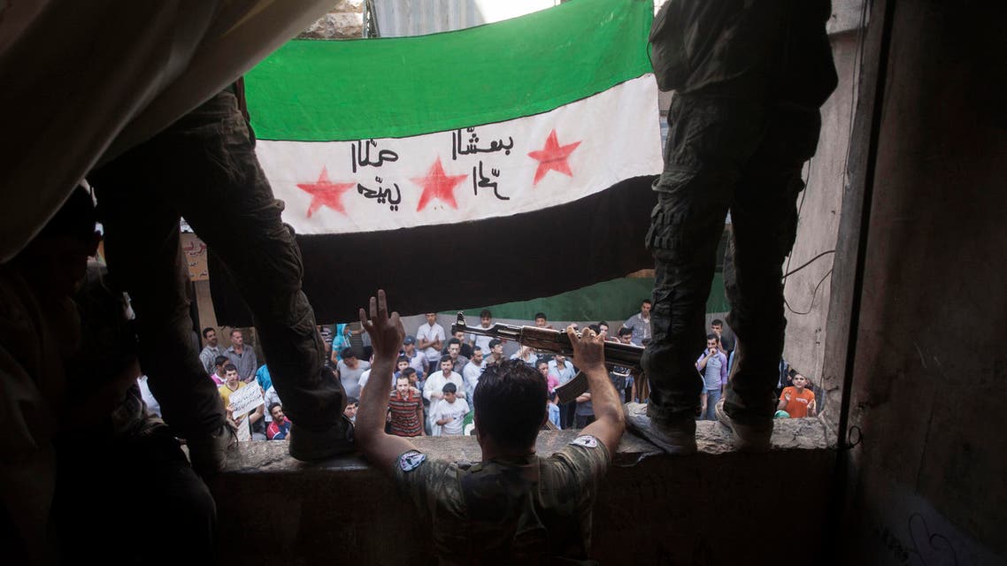 In this Friday, Sept. 21, 2012 file photo, Free Syrian Army rebels hold a revolutionary flag during a demonstration in the Bustan al-Qasr neighborhood of Aleppo, Syria. (File photo: AP)