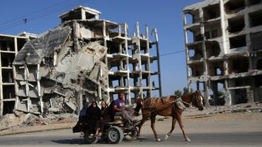 Palestinian family members ride a horse cart as they pass apartment buildings that were destroyed in the last summer's Israel-Hamas war, in the residential neighborhood of Beit Lahiya in the northern Gaza Strip, Tuesday, June 2, 2015. AP