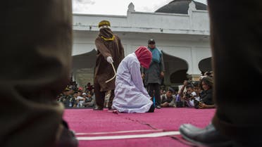 An Acehnese woman convicted for "immoral acts" is lashed by a hooded local government officer during a public caning at a square in Banda Aceh, Aceh province, on June 12, 2015. AFP PHOTO / Chaideer MAHYUDDIN