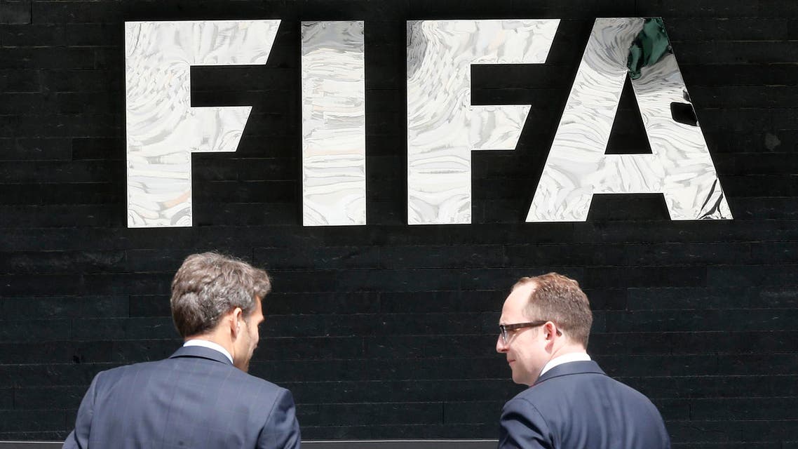 Two men talk to each other in front of the FIFA logo at the FIFA headquarters in Zurich, Switzerland, Wednesday, May 27, 2015. Swiss prosecutors opened criminal proceedings into FIFA's awarding of the 2018 and 2022 World Cups, only hours after seven soccer officials were arrested Wednesday pending extradition to the U.S. in a separate probe of "rampant, systemic, and deep-rooted" corruption. (AP Photo/Michael Probst)